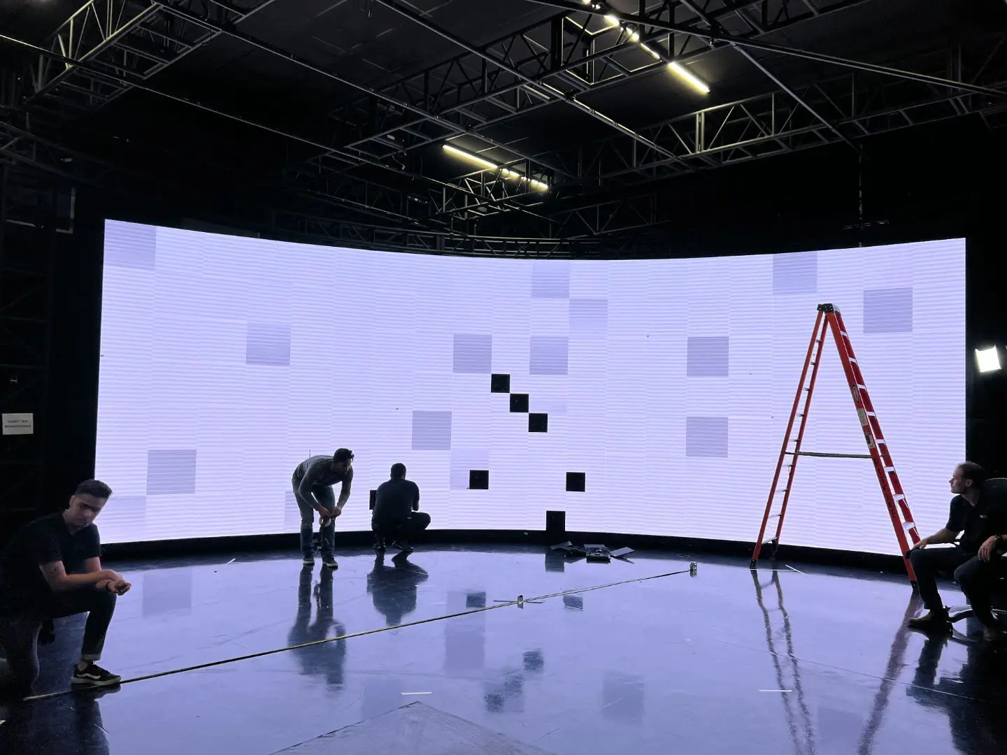 A large screen with people standing around it