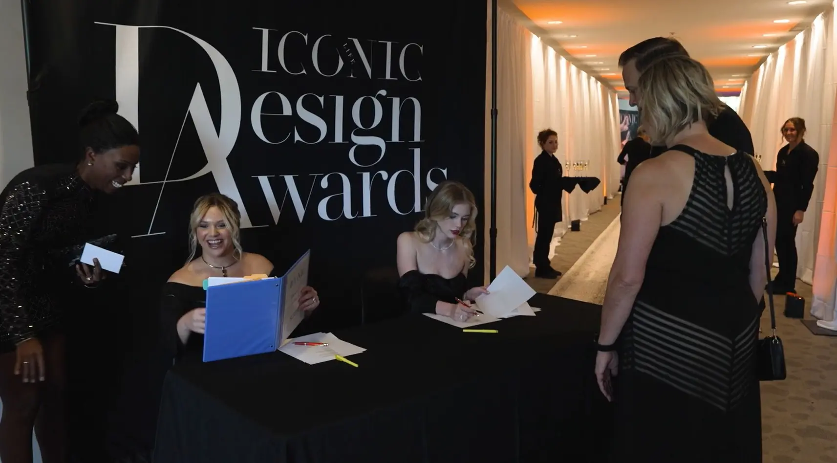 Three women sitting at a table signing papers.