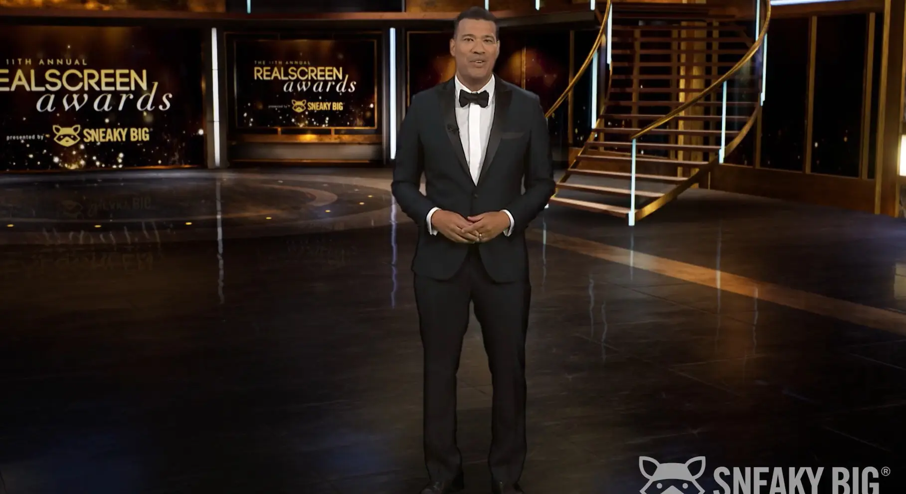 A man in a tuxedo standing on the set of a tv show.